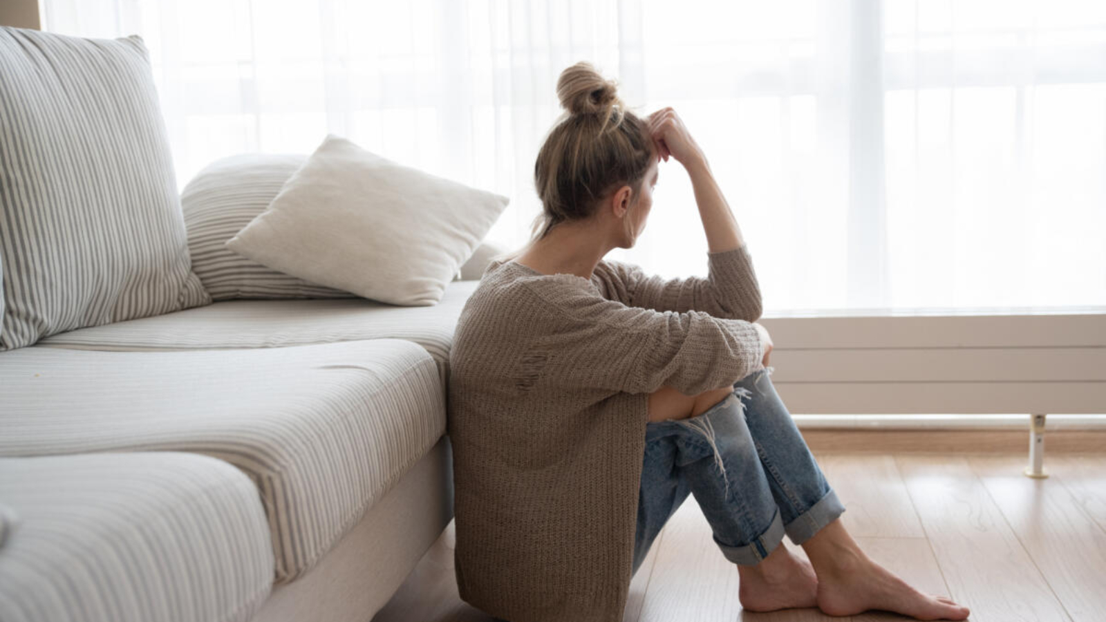 A depressed woman is sitting on the floor in the living room.; Shutterstock ID 1889117734; purchase_order: 10102022; job: Editorial Associate; client: Ellie Spencer-Failes; other: